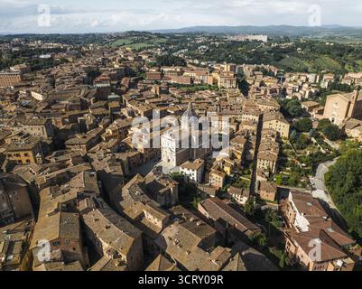 Vista aerea dei tetti in terracotta che si infrangono intorno al Duomo di Siena, gettando ombre attraverso le labirintiche strade della città antica, Siena, Toscana, Italia. Foto Stock