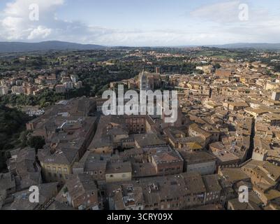 Veduta aerea dei tetti in terracotta che scendono intorno al Duomo di Siena, una sinfonia di umero e ocra sotto il sole toscano, Siena, Toscana, Italia. Foto Stock