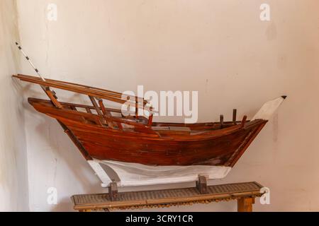 Modello dettagliato in legno di una tradizionale barca araba in sambuco esposta contro una semplice parete luminosa negli Emirati Arabi Uniti Foto Stock