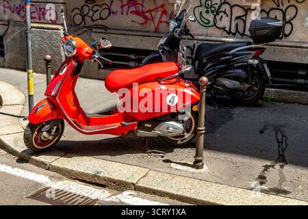 Una Vespa rossa parcheggiata sul marciapiede in via Cesare correnti a Milano, Italia Foto Stock