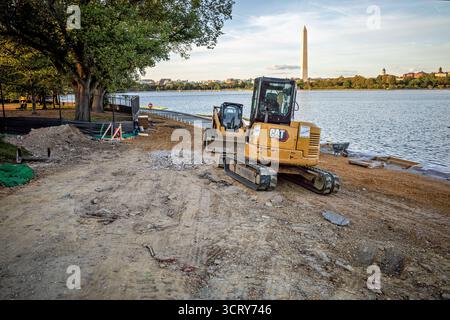 Tidal Basin Seawall Reconstruction Project Washington DC // WASHINGTON DC — Un escavatore CAT e materiali da costruzione sono visibili presso il cantiere del Tidal Basin Seawall Reconstruction Project vicino all'Inlet Bridge il 2 ottobre 2025. Questo progetto critico riguarda il deterioramento delle dighe del bacino delle maree, che subiscono quotidianamente inondazioni dovute al cedimento e all'innalzamento del livello del mare. La ricostruzione mira a ricostruire e innalzare le banchine, proteggendo monumenti iconici come il Jefferson Memorial e il National Mall, incluso il Monumento a Washington visibile. Foto Stock