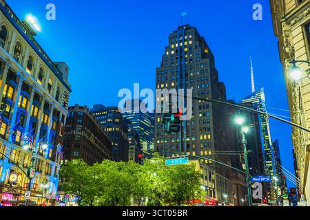 Vista serale dei grattacieli e degli edifici illuminati sulla West 34th Street con semafori e alberi. New York. STATI UNITI. Foto Stock