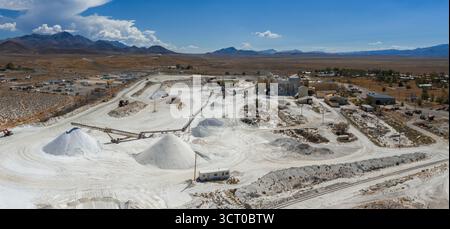 Vista aerea di un sito minerario del sale in Nevada con tumuli di sale bianco, edifici industriali, strade sterrate, binari ferroviari e un vasto paesaggio desertico. Foto Stock