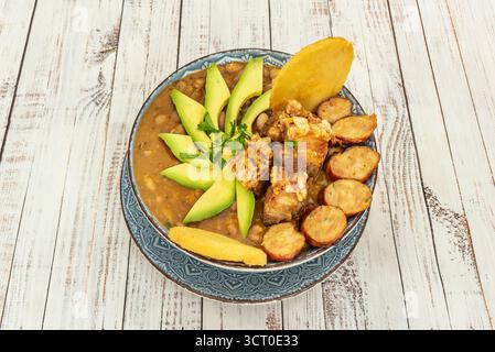Trippa spessa Bogotá con trippa di manzo, verdure tritate e condimenti, servita in una pentola di argilla con avocado e peperoncino. Foto Stock