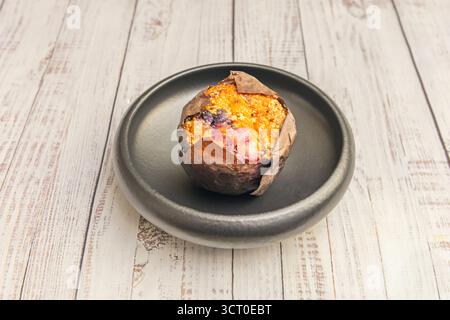 Muffin al limone con glassa agli agrumi e scorza gialla, brillanti sulle ossa di porcellana con accenti blu cobalto Foto Stock