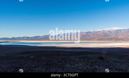 La luce dell'alba sulla catena Panamint si riflette nel temporaneo lago Manly a Badwater Basin, nel Parco Nazionale della Valle della morte Foto Stock