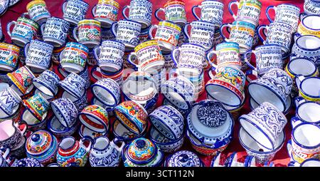 Una grande collezione di tazze colorate con scritta ebraica su di esse. Le tazze sono disposte in pile su un tavolo. Città di Puebla, Messico, artigianato Foto Stock