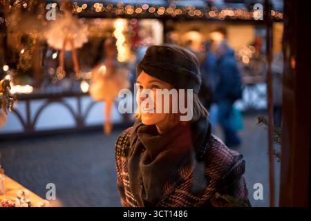 Bella donna è con interesse che guarda la piccola ballerina come decorazione natalizia sul tradizionale mercato di Natale in Germania. Verticale Foto Stock