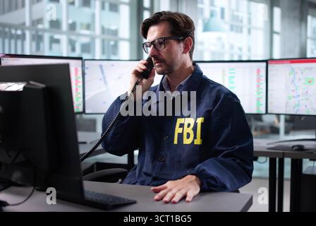 Agente dell'FBI senior che parla al telefono cellulare alla scrivania dell'ufficio. Foto Stock