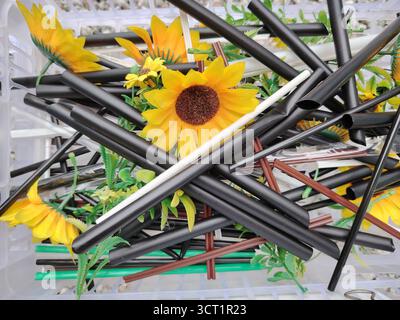 Cannucce colorate e girasoli artificiali in un cestino di plastica Foto Stock