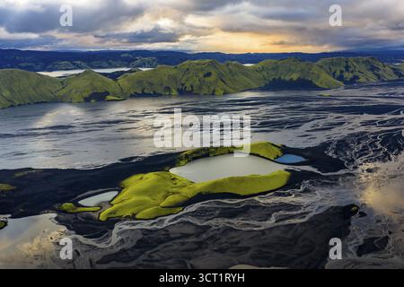 Lago cratere di colore turchese con bordi crateri ricoperti di muschio negli altopiani islandesi, circondato da fiumi glaciali, l'Islanda Foto Stock