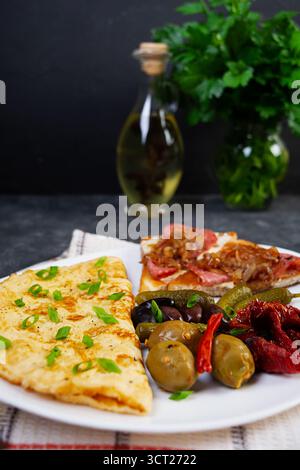 Omelette con pane tostato, olive e pomodori secchi. Gustosa colazione con omelette Foto Stock
