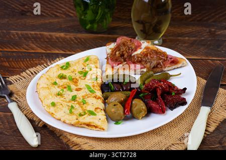 Omelette con pane tostato, olive e pomodori secchi. Gustosa colazione con omelette Foto Stock