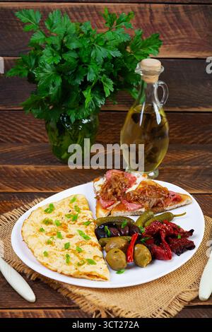 Omelette con pane tostato, olive e pomodori secchi. Gustosa colazione con omelette Foto Stock