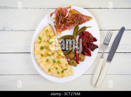Omelette con pane tostato, olive e pomodori secchi. Gustosa colazione con omelette Foto Stock