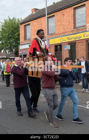La fiera del polo di Corby si svolge a Corby Old Village una volta ogni vent'anni. La Charter Fair fu concessa dalla regina Elisabetta i nel 1585. Il sindaco, consigliere Tafadzwa Chikoto è presieduto, portato a spalla in alto su due pali intorno al villaggio tra la lettura della carta reale all'inizio della manifestazione e la dichiarazione di apertura della Fiera. Corby. Northamptonshire, Inghilterra 3 giugno 2022 2020s UK HOMER SYKES Foto Stock
