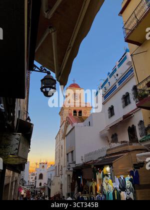 La storica torre della chiesa e i balconi in ferro battuto sopra il vivace suk nella vecchia Medina, Tangeri, Marocco, 4 ottobre 2025. Foto Stock