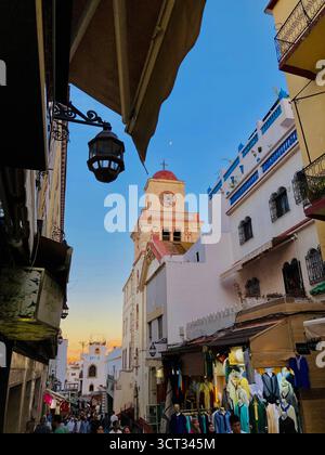 La storica torre della chiesa e i balconi in ferro battuto sopra il vivace suk nella vecchia Medina, Tangeri, Marocco, 4 ottobre 2025. Foto Stock