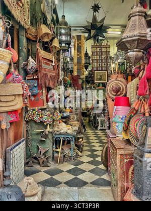 Interno di un tradizionale negozio di antiquariato a Tangeri, Marocco. Lanterne artigianali, ceramiche, tessuti e manufatti culturali. 2 ottobre 2025 Foto Stock