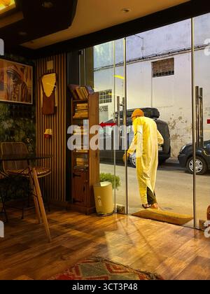 Vista interna di una caffetteria marocchina locale a Tangeri. Illuminazione calda, arredamento tradizionale e attività di strada all'aperto. Catturato il 2 ottobre 2025. Foto Stock
