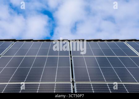Pannelli solari che coprono un tetto residenziale, che sfruttano la luce solare per generare energia elettrica pulita e sostenibile per le abitazioni Foto Stock