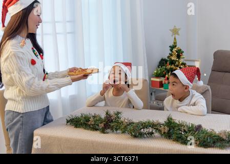 Le famiglie di Natale amano i pasti natalizi a casa, i genitori servono pizza per i bambini, con decorazioni a casa Foto Stock