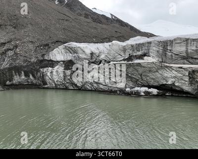 Vista ravvicinata dettagliata della parete verticale e fratturata di un ghiacciaio, dove incontra il laghetto di acqua dolce verde pallido Foto Stock