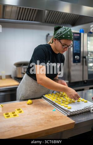 Piacenza, Italia - 25 settembre 2025 giovani donne realizzano con cura tortelli pasta ripiena che incarnano la produzione alimentare artigianale e culinario italiano Foto Stock