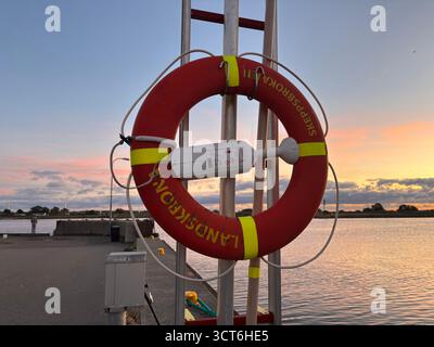 Anelli salvagente di emergenza su cavalletti posizionati accanto all'acqua in Svezia e Danimarca, compresi dispositivi galleggianti arancioni con linee collegate per il lancio Foto Stock