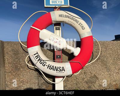 Anelli salvagente di emergenza su cavalletti posizionati accanto all'acqua in Svezia e Danimarca, compresi dispositivi galleggianti arancioni con linee collegate per il lancio Foto Stock