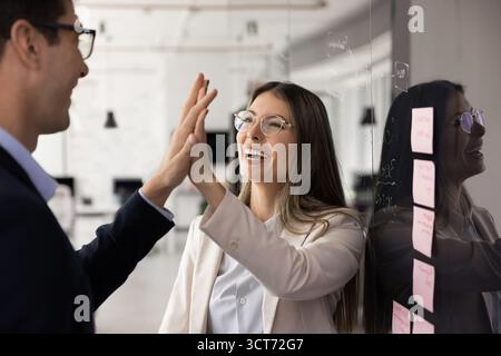 Felice giovane donna d'affari latina che batte cinque mani alte con la collega Foto Stock