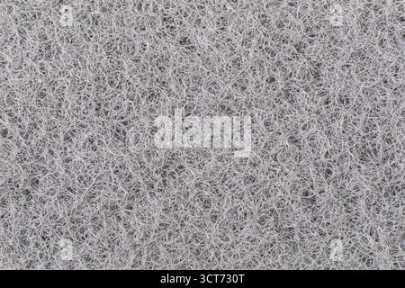 Vista macro della superficie della trama dello strato di spugna scrubber da cucina nera e dello sfondo. Foto Stock