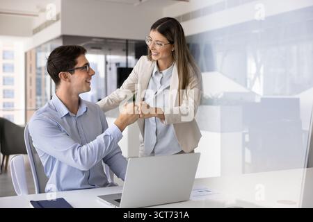 Due giovani colleghi allegri che celebrano il successo del lavoro di squadra Foto Stock