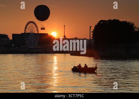 Maestoso tramonto sul fiume Vistola con una barca che si sposta dolcemente, creando una scena pittoresca e tranquilla Foto Stock