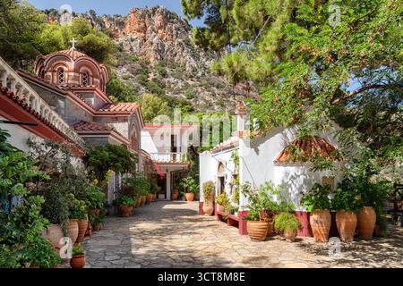 Monastero di San Giorgio, Creta, Grecia - 2 settembre 2025: Vista panoramica del tradizionale cortile del monastero greco-ortodosso con sentiero in pietra, vaso Foto Stock