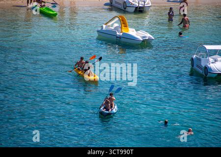Persone che amano gli sport acquatici nel mare turchese cristallino in una giornata di sole, kayak e pedalò durante le loro vacanze estive in Grecia Foto Stock
