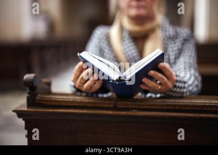 La donna cristiana sta leggendo la bibbia e pregando in chiesa. Preghiera silenziosa a Dio. Concetto di religione e spiritualità Foto Stock