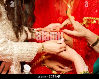 Donna che applica pasta di henné alla mano della sposa durante la cerimonia pre-matrimonio curdo-tunisina. Foto Stock