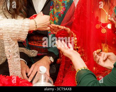 Donna che applica pasta di henné alla mano della sposa durante la cerimonia pre-matrimonio curdo-tunisina. Foto Stock