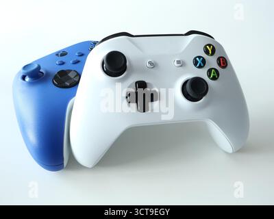 Due controller di gioco wireless, uno bianco davanti e uno blu dietro, creano una configurazione di gioco dinamica. Immagine stock ideale per giochi, tecnologia e. Foto Stock