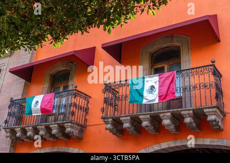 Due balconi con bandiere appese. Una delle bandiere è una bandiera messicana. Centro storico di Queretaro, architettura coloniale, decorazioni per Foto Stock