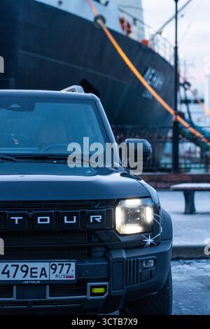 Murmansk, Russia - 13 dicembre 2024: Un dettaglio estremamente ravvicinato del faro anteriore, della griglia e della targa di un SUV Jetour T2 scuro con il da Foto Stock