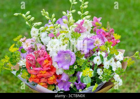 Bouquet di fiori avvolti di fiori primaverili misti. Splendida disposizione di fiori freschi color pastello. Bouquet di compleanno con draghi di dentini, matthiola Foto Stock