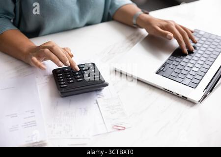 Donna professionista che utilizza un computer portatile e una calcolatrice Foto Stock