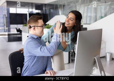 Manager felice che dà cinque alti a un dipendente con sindrome di Down Foto Stock