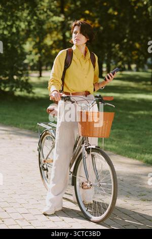 Bicicletta da passeggio per donna caucasica con smartphone all'aperto Foto Stock