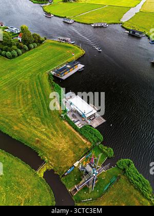 Vista aerea del tortuoso fiume con barche, moderni moli, e tradizionali campi lussureggianti e canali mulini a vento fondono patrimonio culturale e ricreazione in una tranquilla campagna Foto Stock