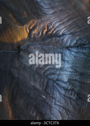 Vista aerea del paesaggio aspro e lunare, dove le ombre approfondiscono la struttura del terreno accidentato, contrastando la luce dorata, Goreme, Nevsehir, Turkiye. Foto Stock