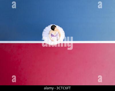 Vista aerea di una ballerina in un tutu bianco, un netto contrasto con il vibrante sfondo rosso e blu, creando un affascinante equilibrio di colore e forma, Adelaide, Australia meridionale, Australia. Foto Stock