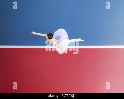 Veduta aerea di una ballerina in un tutù bianco che salta con grazia su uno sfondo vibrante di rosso e blu contrastanti, Adelaide, Australia meridionale, Australia. Foto Stock